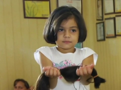 Menina doa cabelo para crianças com câncer